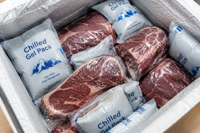 Chilled gel packs keeping vacuum-sealed meat safe inside an insulated delivery box