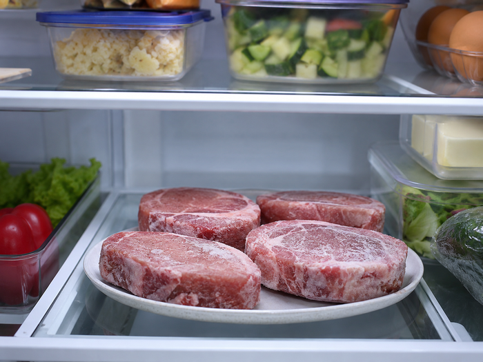 Frozen meat defrosting slowly on a plate in the fridge