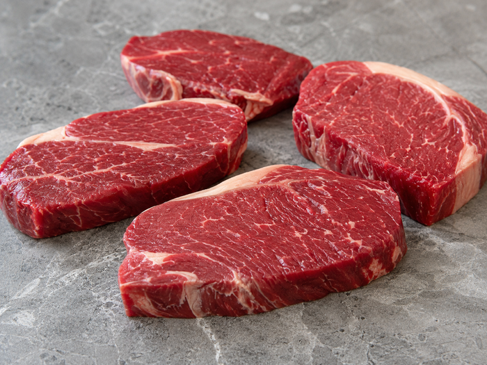 Raw grass fed beef steaks with deep red colour on a stone benchtop