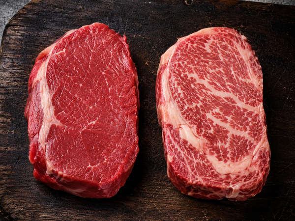 Grass-fed and grain-fed beef steaks side by side comparing colour and marbling