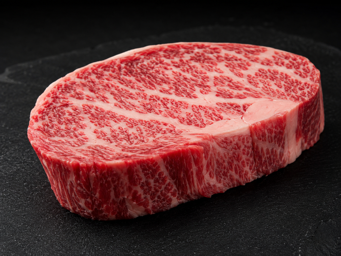 Raw Wagyu beef steak with intense marbling on a dark board