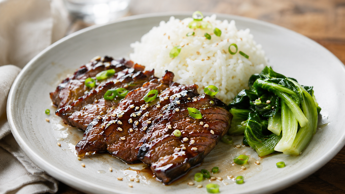 Asian oyster blade roast glazed with ginger, honey and soy, sliced and glossy on a wooden board
