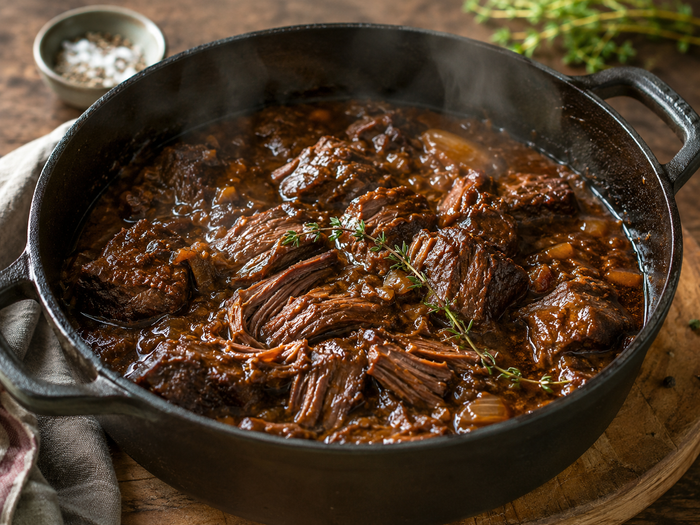 Slow cook beef in the oven, fall-apart braised beef in a cast iron pot with rich gravy