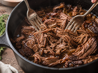 Slow cooked beef chuck shredded in a cast iron pot with rich braising liquid