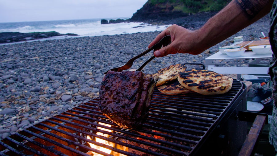 Tomahawk steak grilling over open flame on the Australian coast