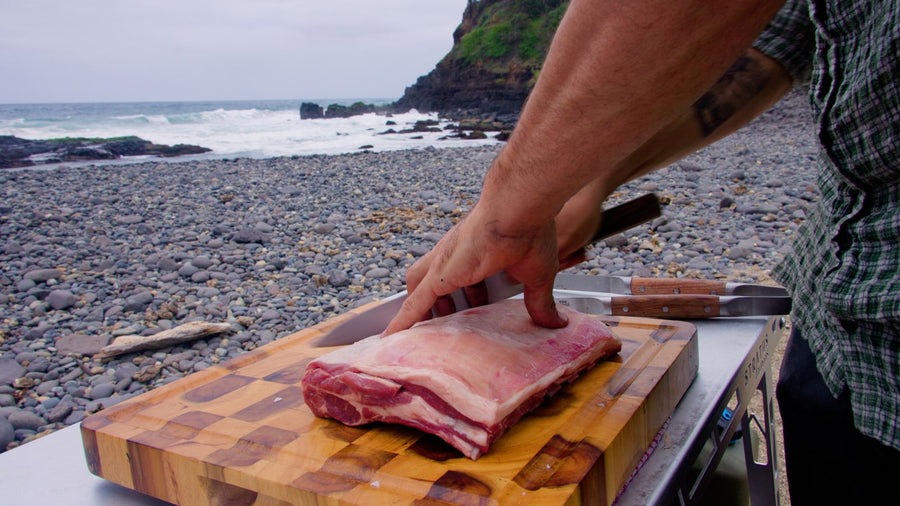 Butcher prepping pork belly on a board by the Australian coast